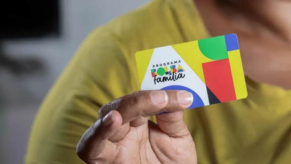 Beneficiário segurando cartão do Bolsa Família durante pagamento de agosto 2025
