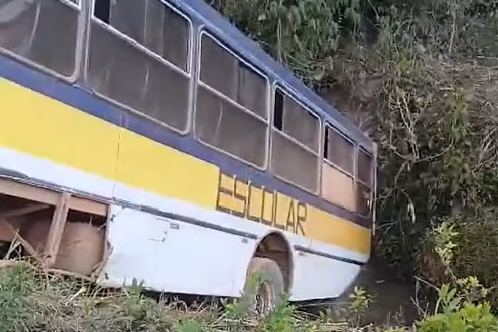 Vista lateral de um ônibus escolar caído dentro de um córrego raso no bairro Tipuana, em Lavras, MG