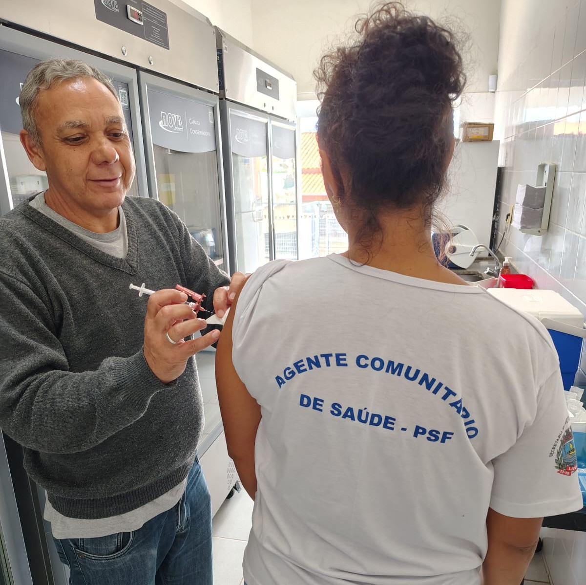 Clique para ver quem pode se vacinar contra a dengue em Lavras agora. Profissional de saúde de Lavras recebendo a dose única da vacinação contra dengue em uma unidade básica de saúde (UBS).